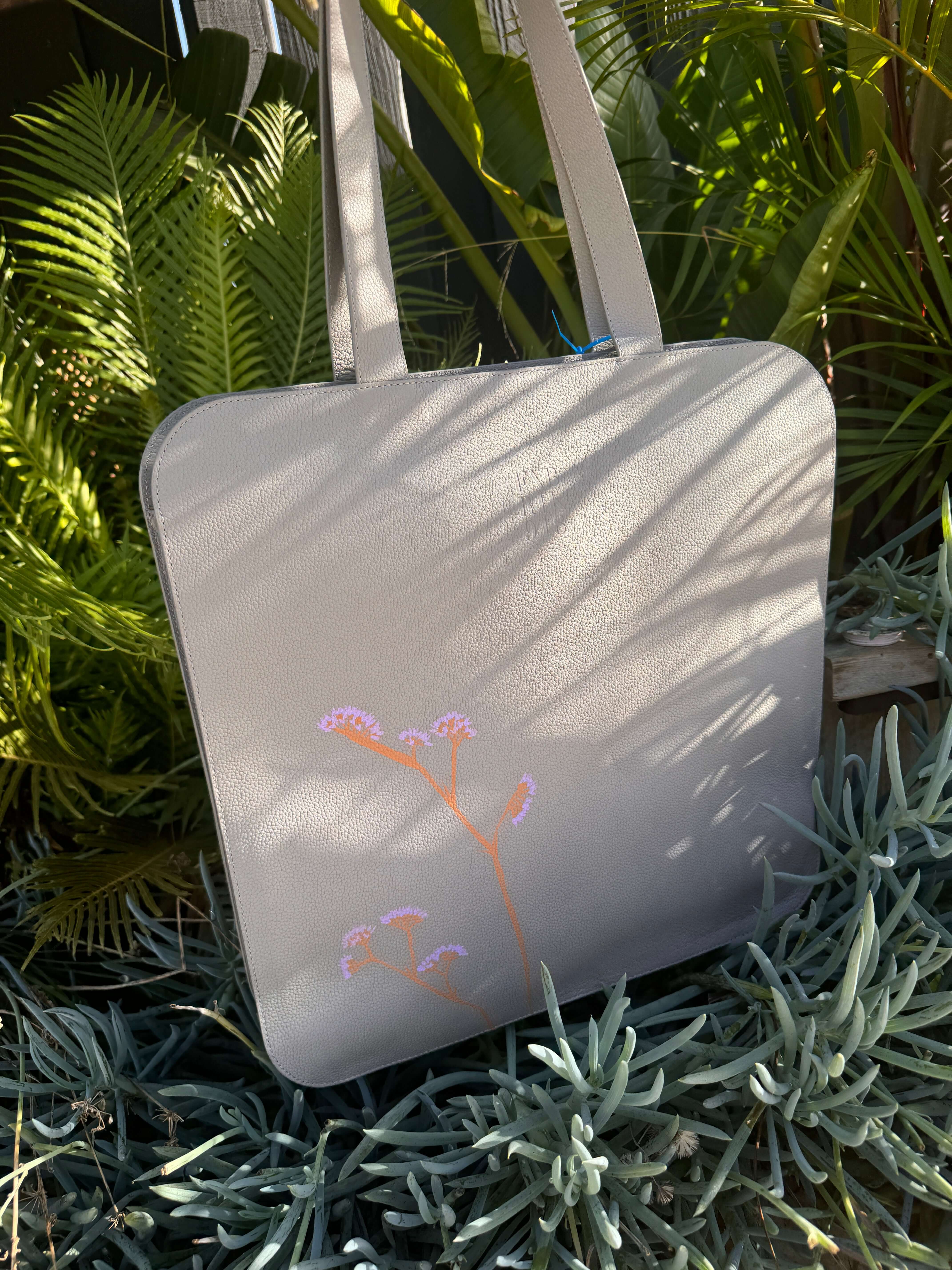 Sea Lavender Leather Laptop Tote Bag with extra wide strap, handcrafted and stylish, ideal for 17-inch laptops, displayed outdoors.